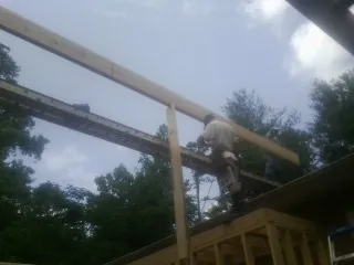 Carpenter setting a ridge beam over a new addition frame — Ice Dam Removal by Roofing Brothers in Kingsland