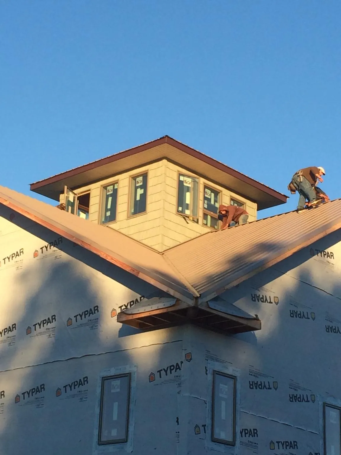 Roofers working around a rooftop cupola on a new metal roof at sunset — Roof Waterproofing in Kingsland by Roofing Brothers